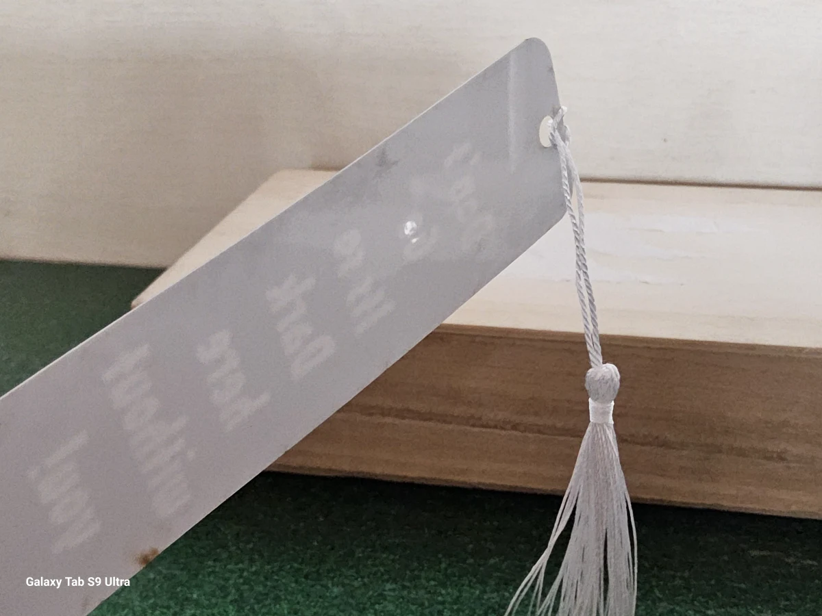 Glossy silver back of engraved bookmark with white tassel